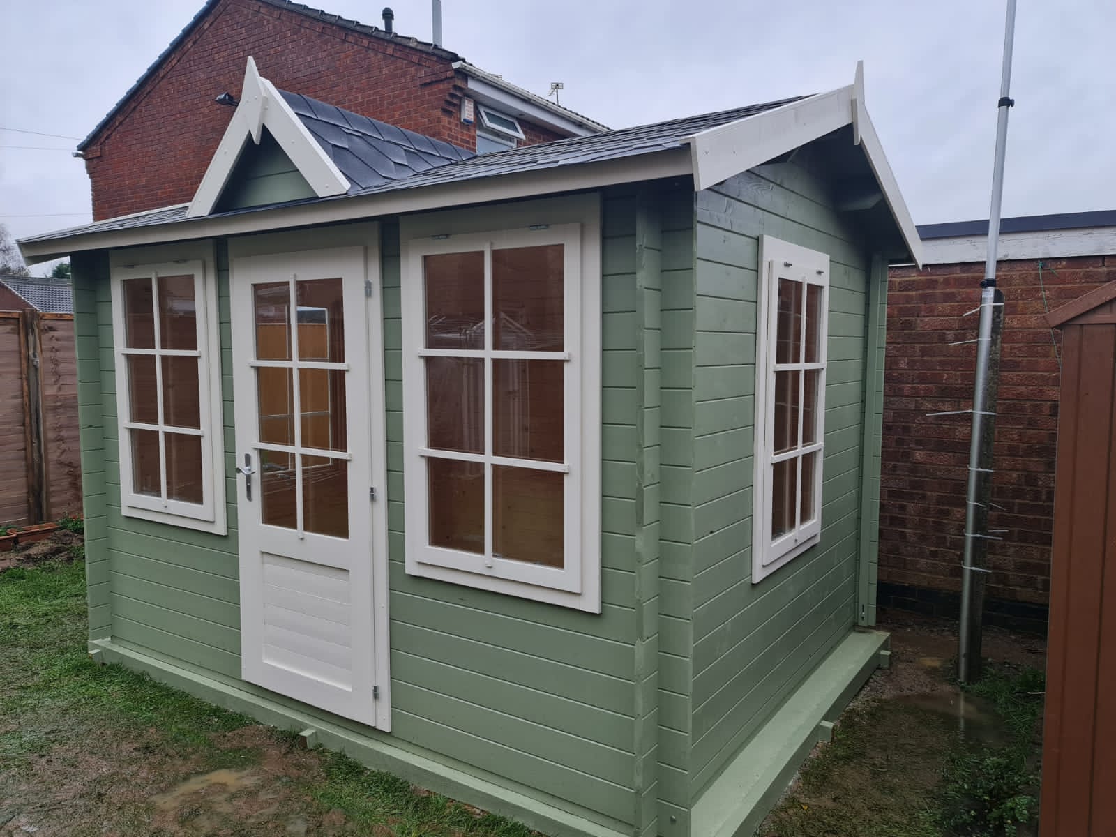A green and white shed with a roof and windows