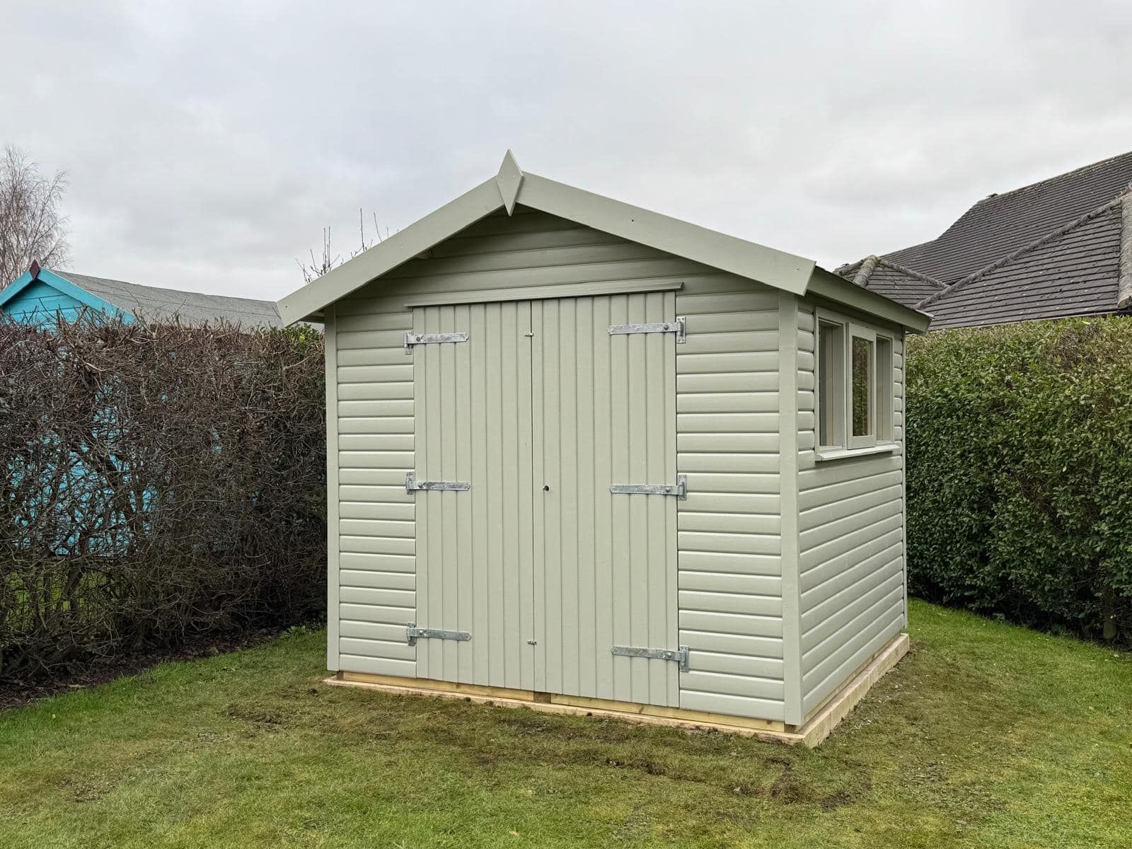 A small white shed is sitting in the middle of a lush green field.