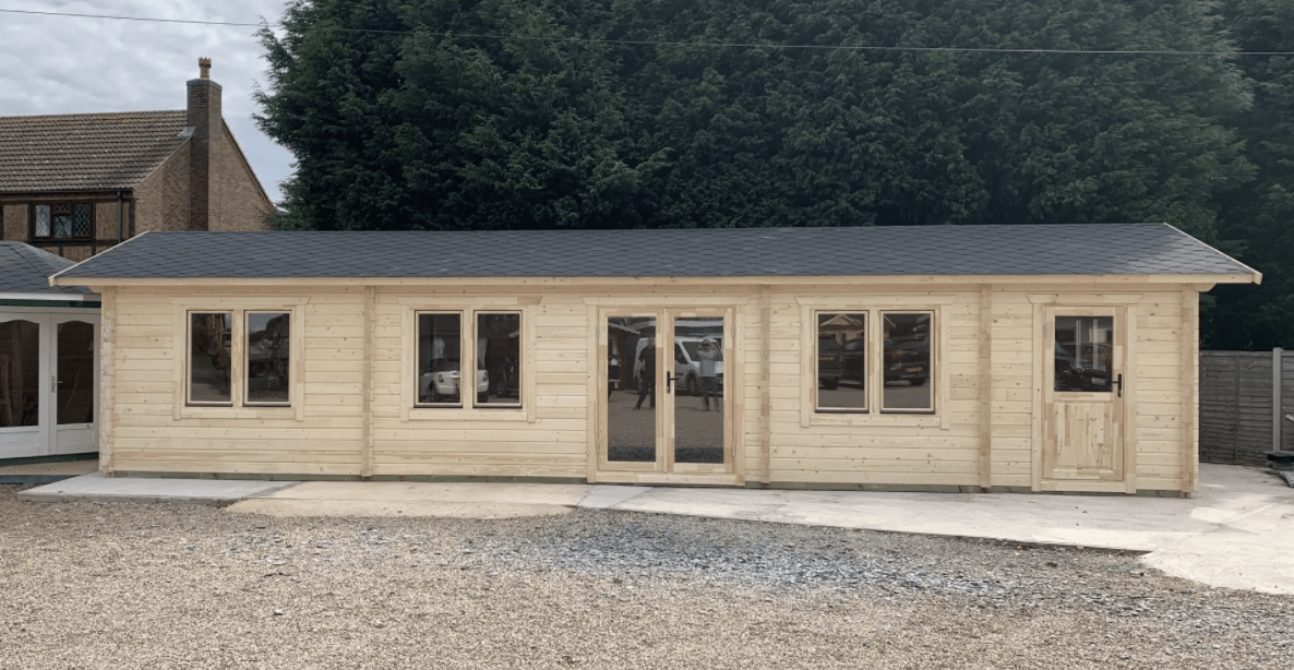 A large wooden house with a gray roof is sitting on top of a gravel lot.