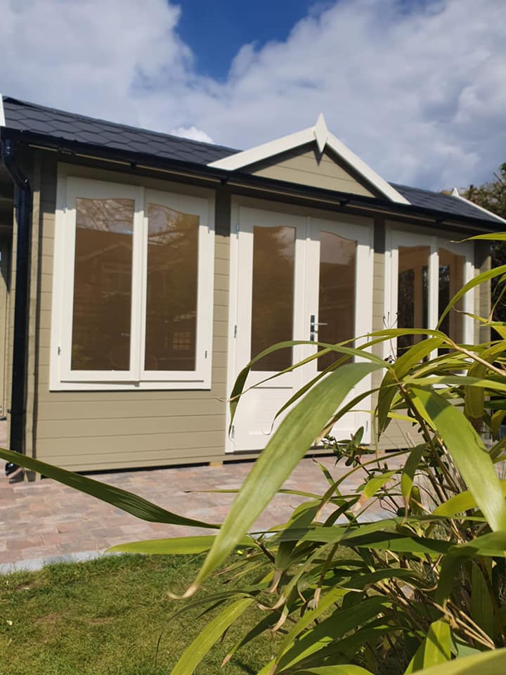 A house with a lot of windows and doors is surrounded by plants.