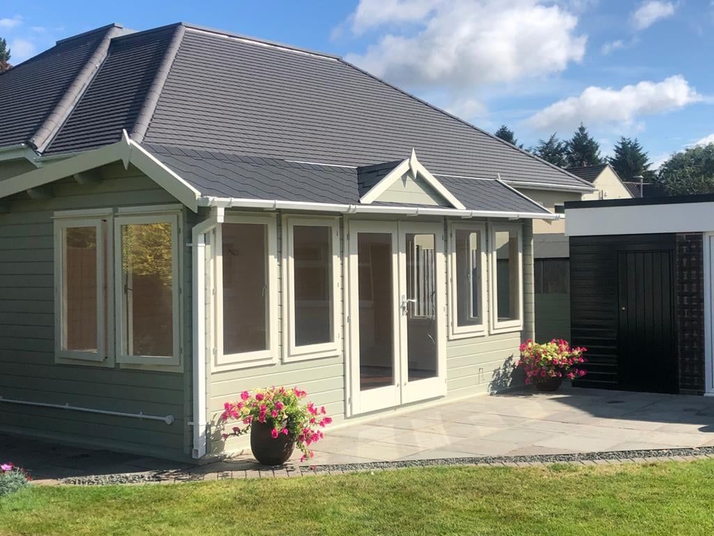 A small house with a gray roof and a patio in front of it.