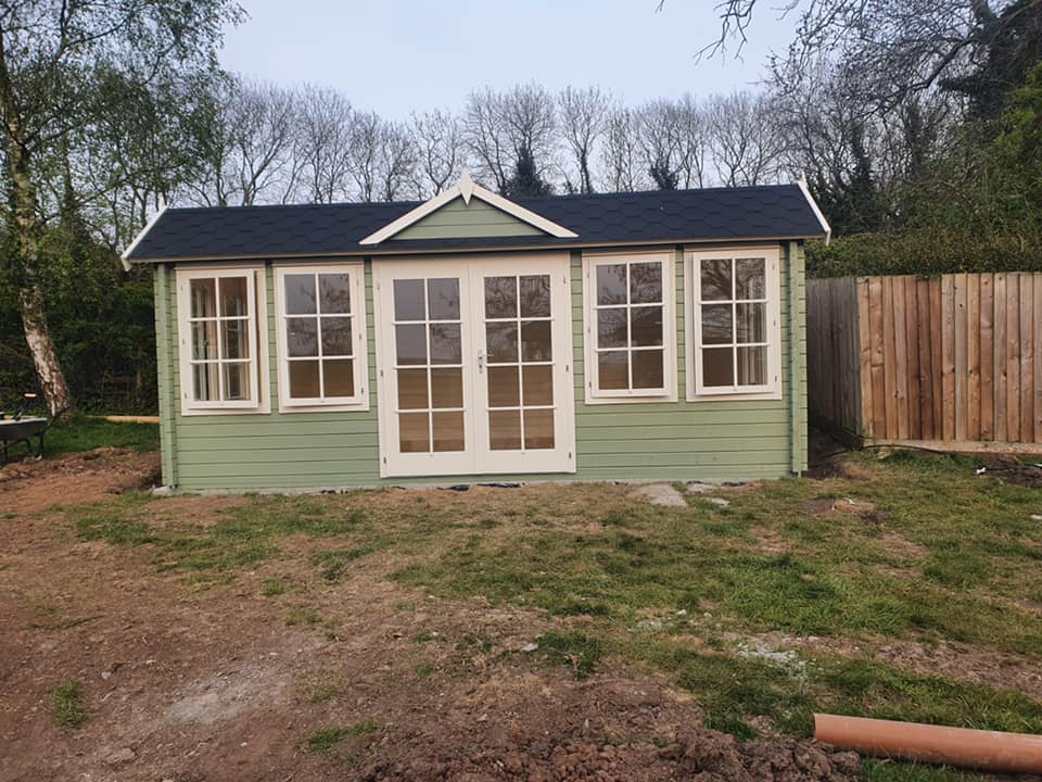 A green house with a black roof and white trim