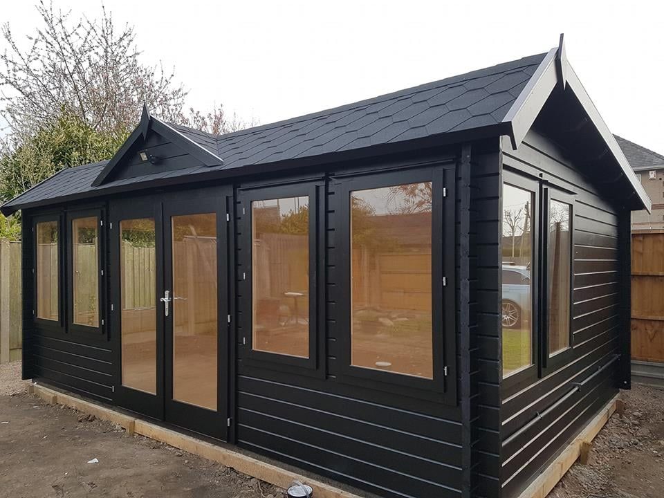 A black lof cabin classroom with a roof and lots of windows