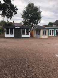 A group of houses are sitting next to each other in a gravel lot.