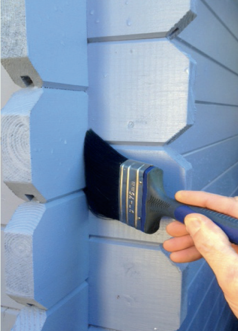 A person is using a brush to paint a blue wall