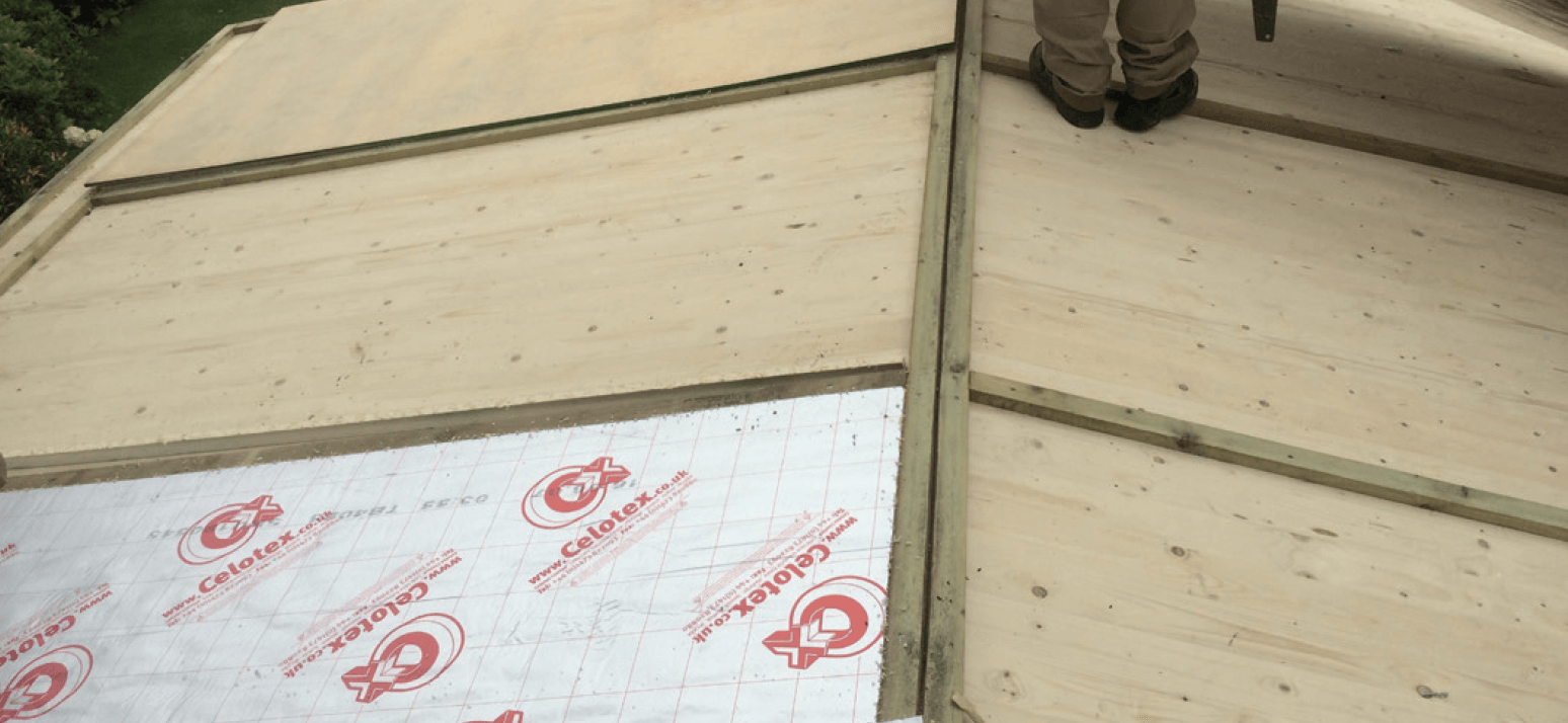 A person is standing on top of a wooden roof.