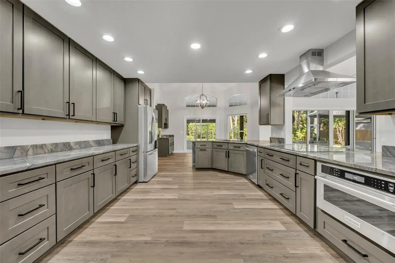 A kitchen with gray cabinets , granite counter tops , and stainless steel appliances.