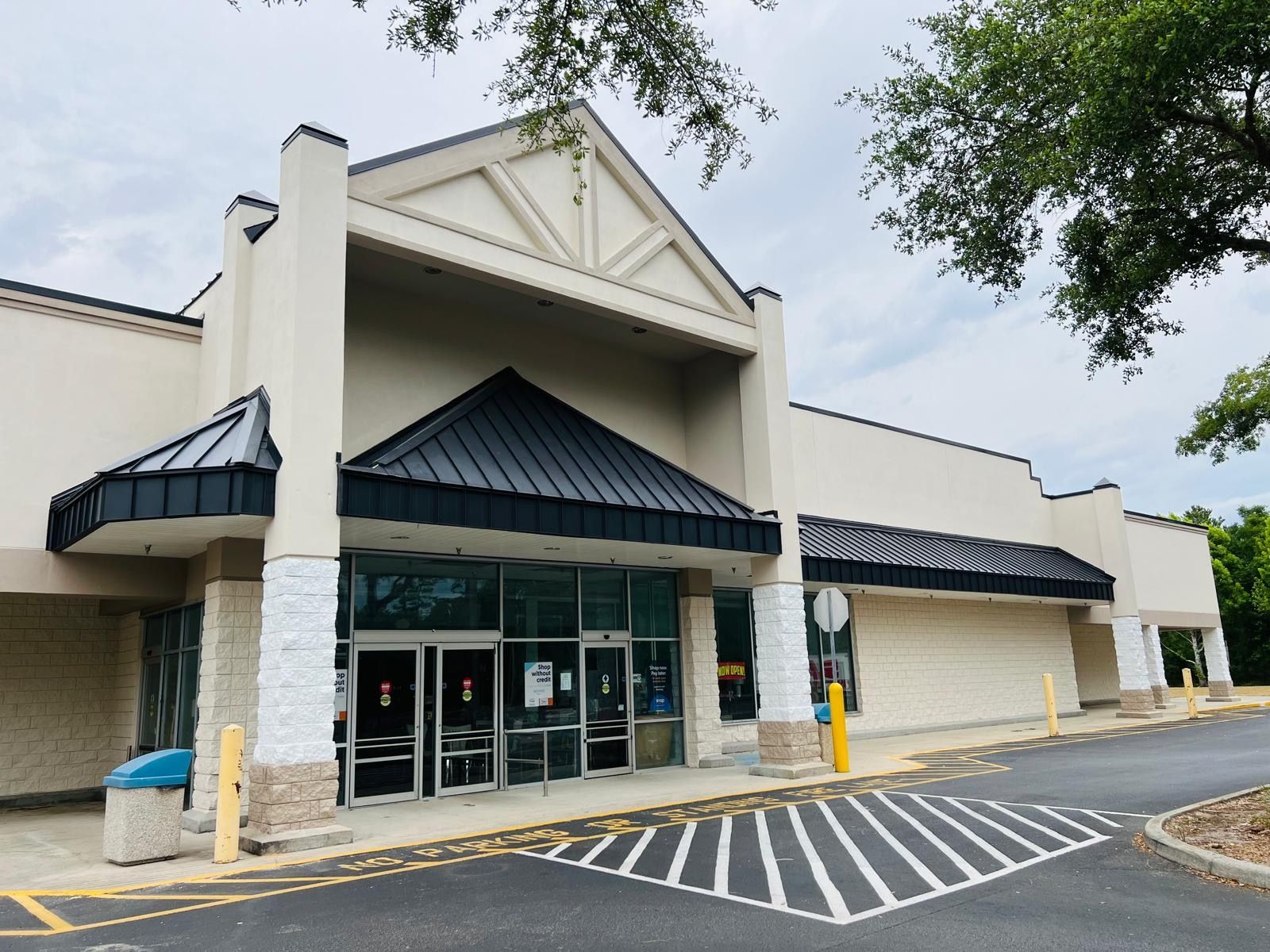 A white building with a black roof and a parking lot in front of it