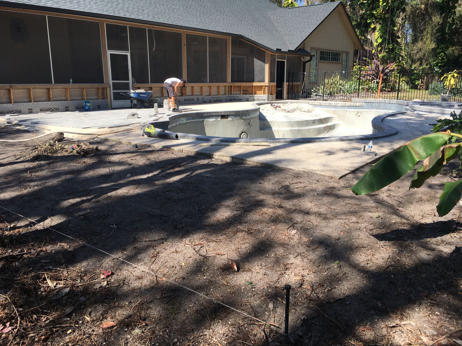 A house with a screened in porch and a pool in front of it
