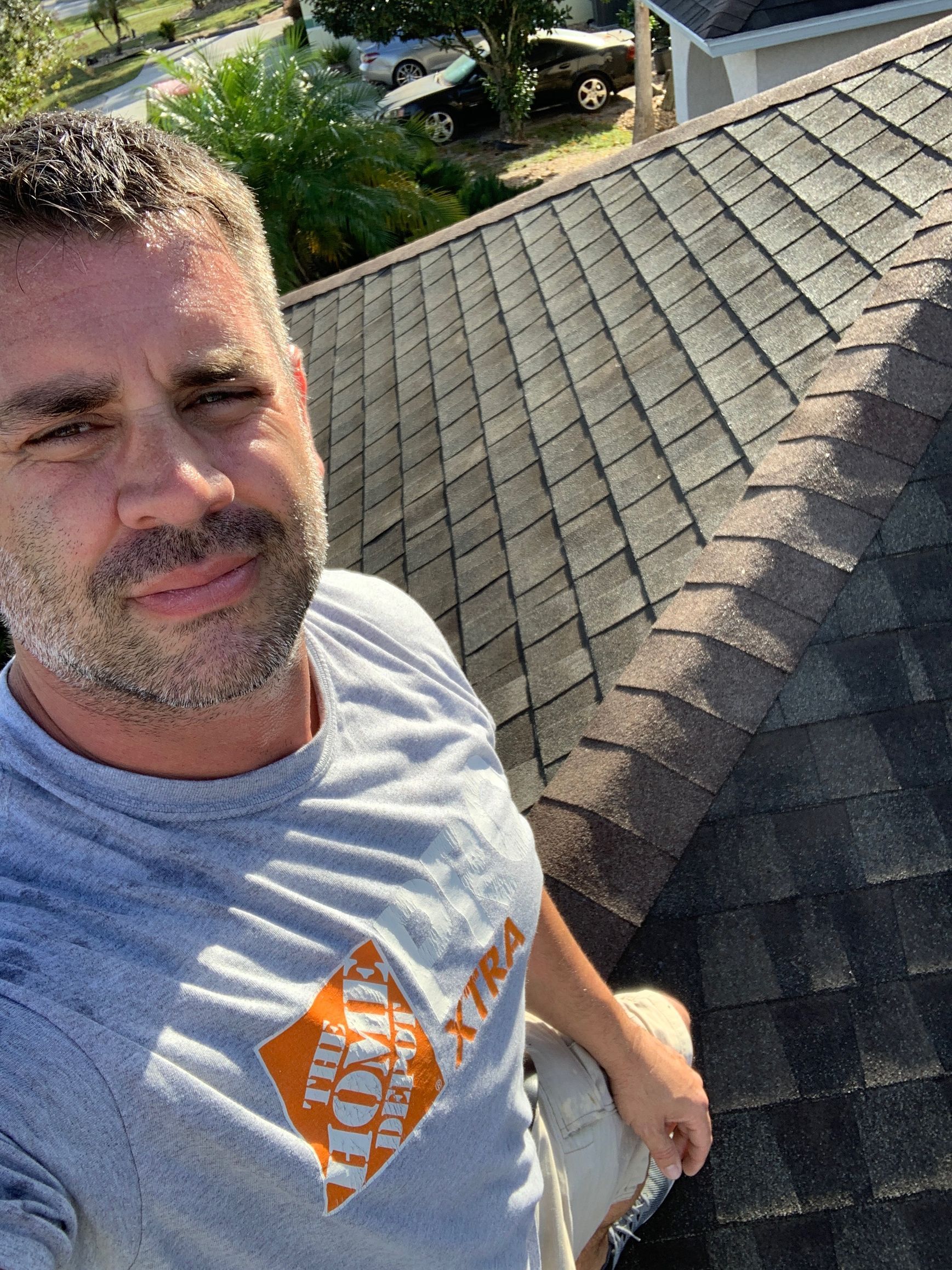 A man is taking a selfie on the roof of a house.