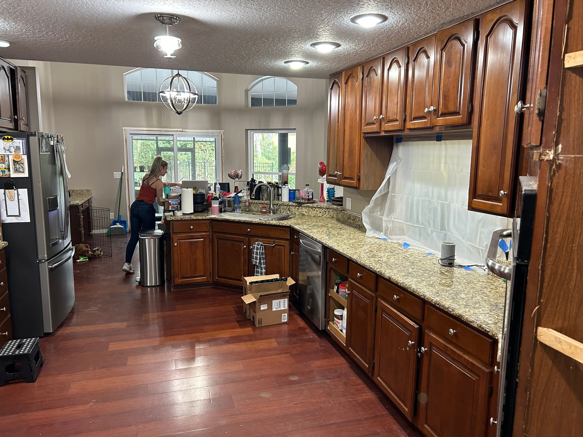 A woman is standing in a kitchen with wooden cabinets and granite counter tops.