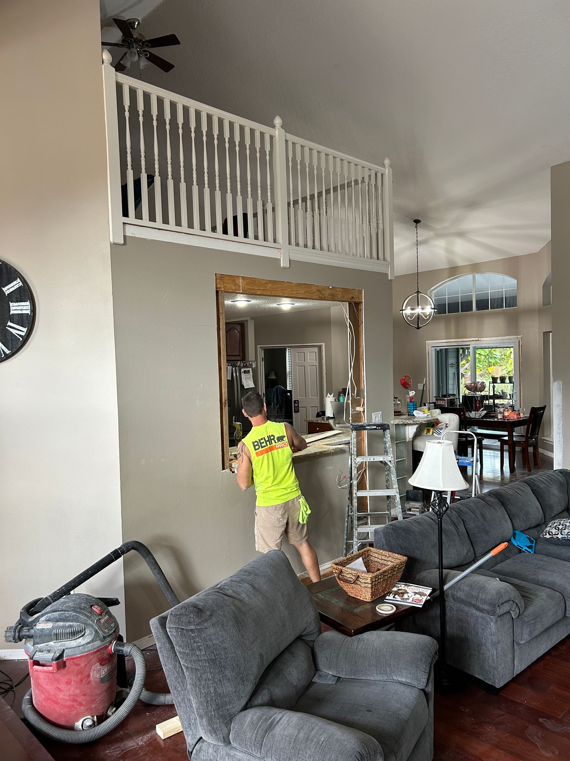 A boy in a yellow shirt is standing in a living room next to a couch.