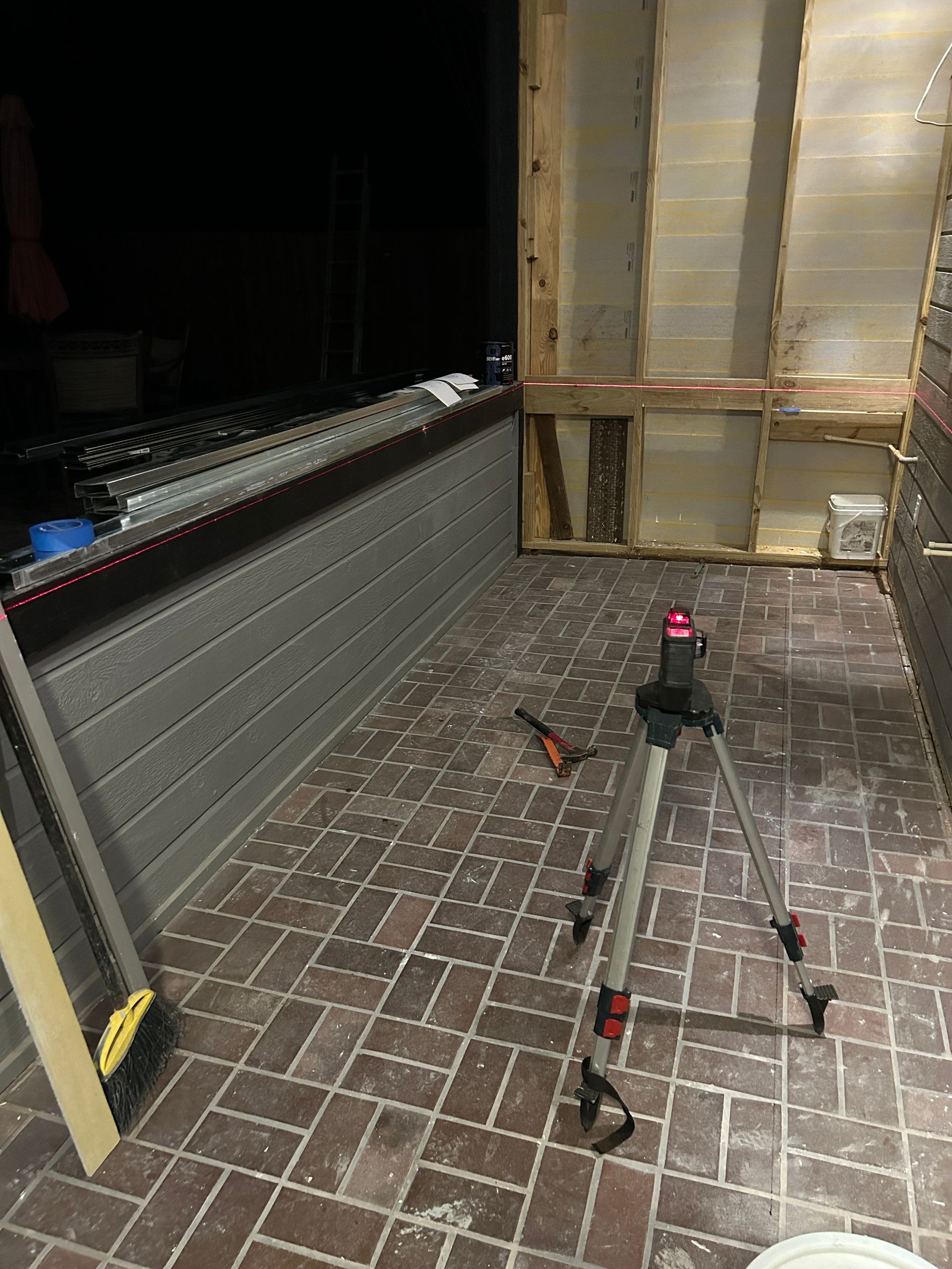 A tripod is sitting on a brick floor in a room.