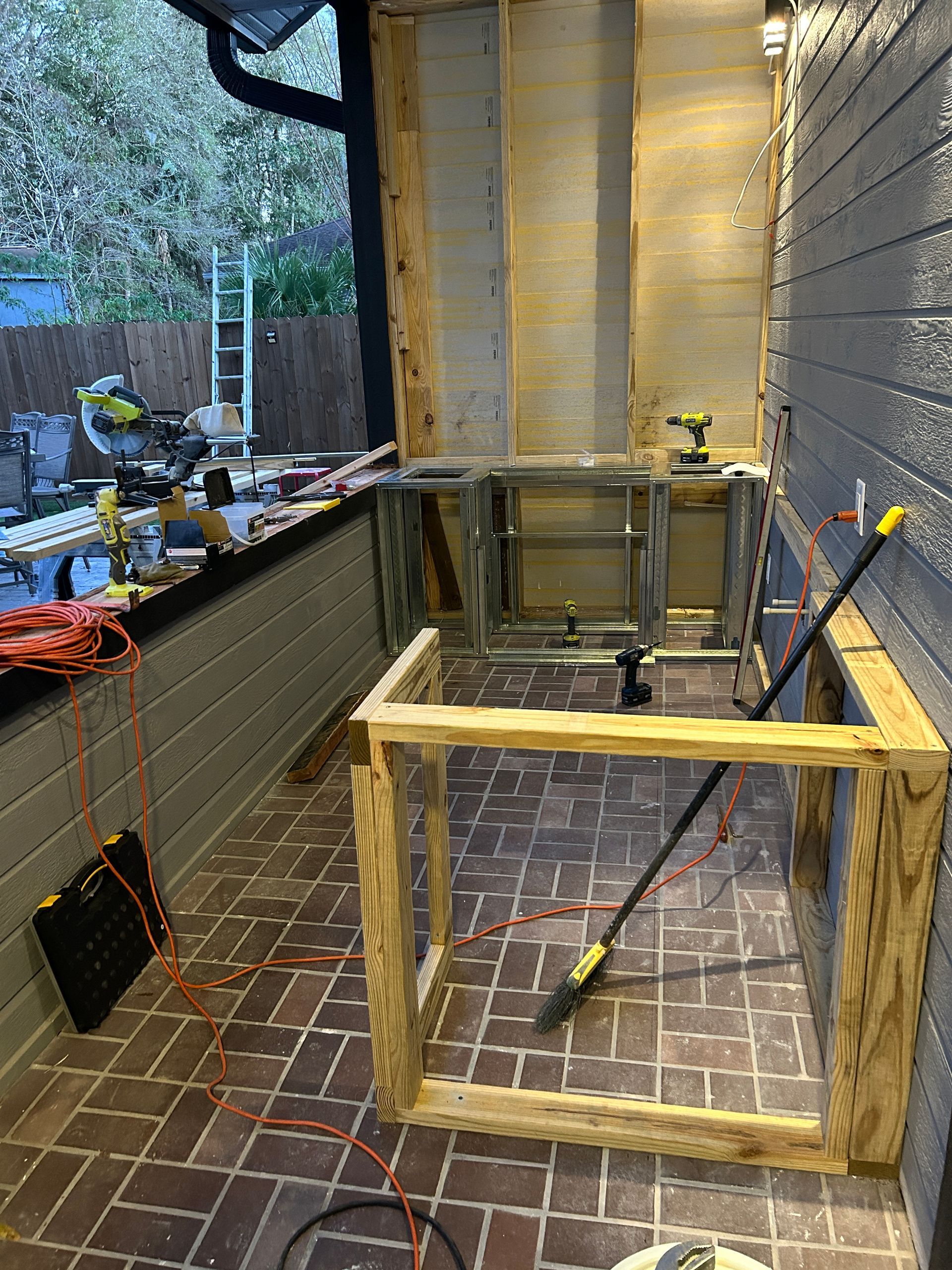 A wooden frame is sitting on a brick floor next to a brick wall.