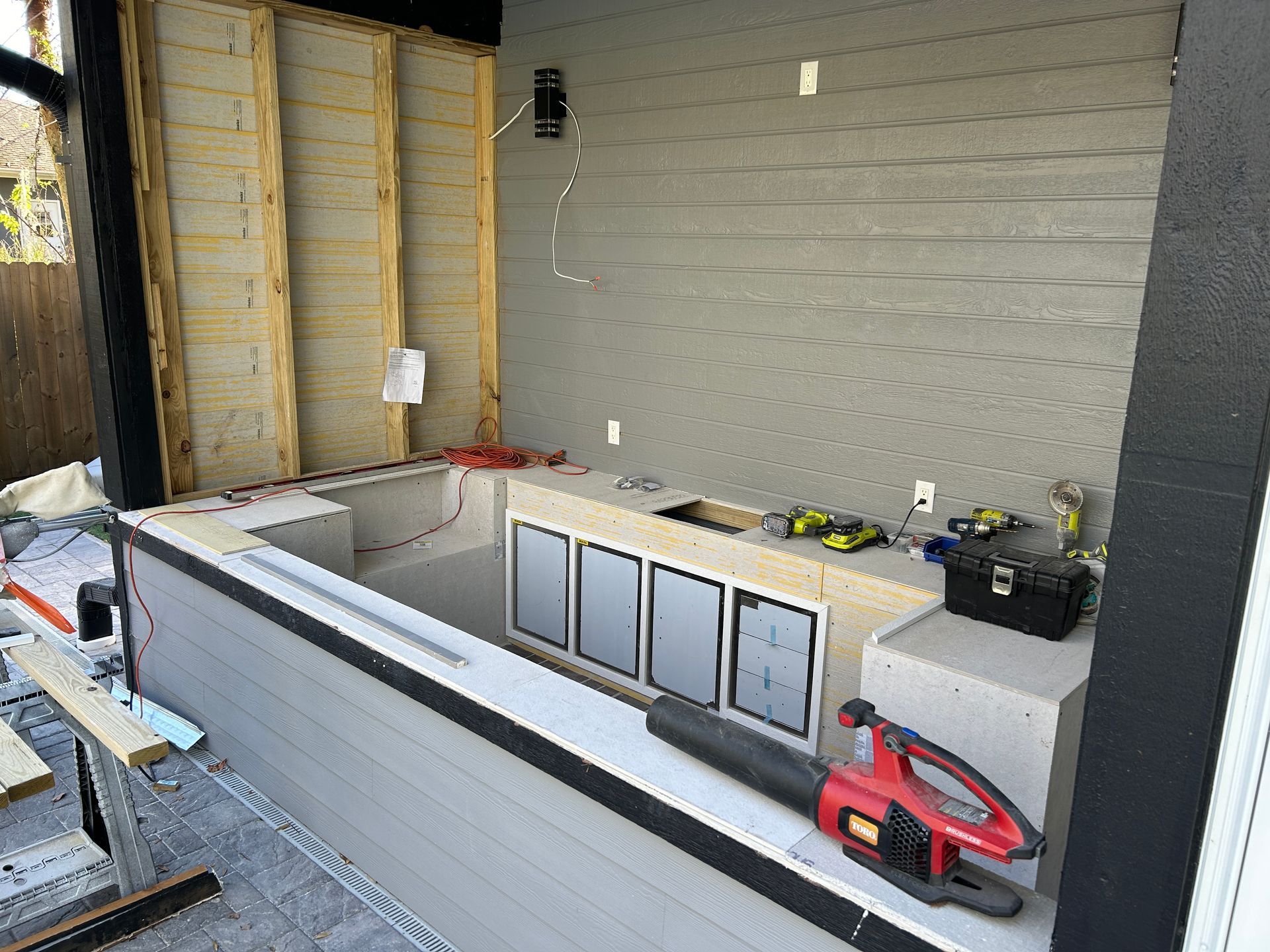 A red and black blower is sitting on a counter in a kitchen under construction.