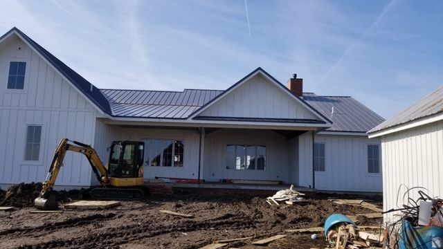 A large white house with a blue roof is being built.