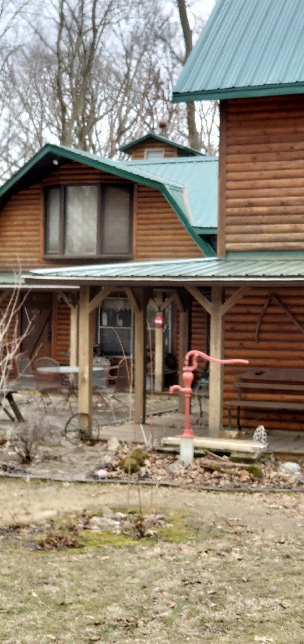 A log cabin with a green roof and a porch.