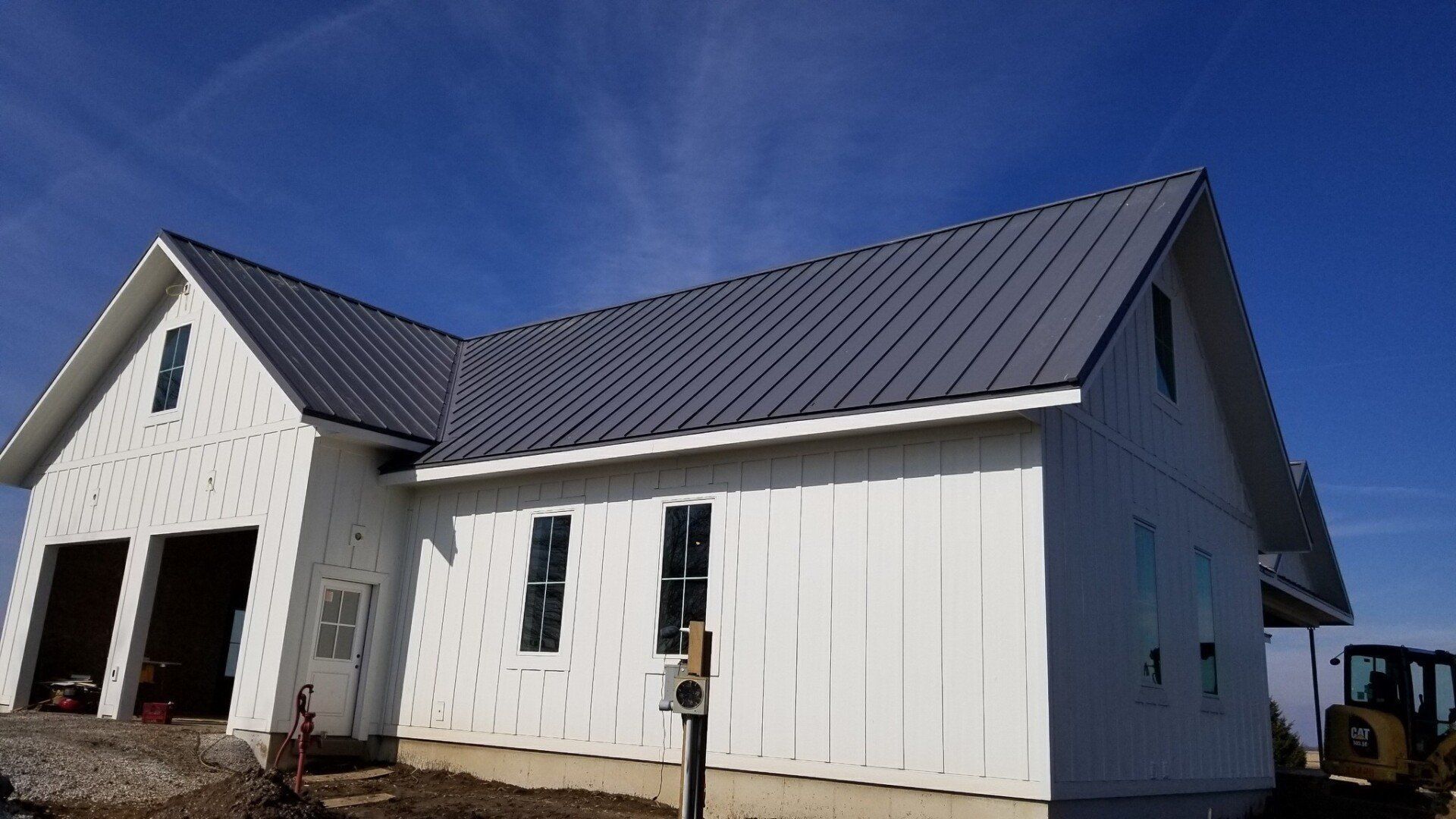 A white house with a black roof is being built.