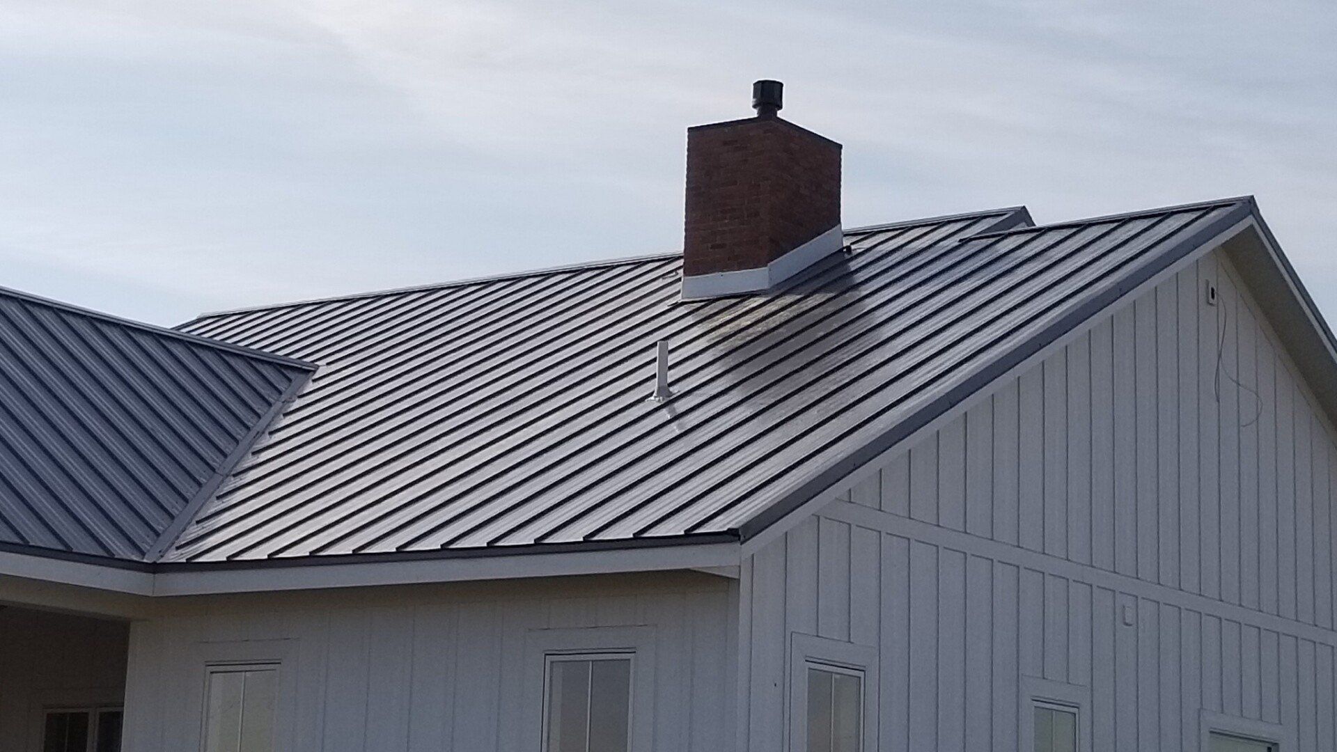 A white house with a metal roof and a chimney