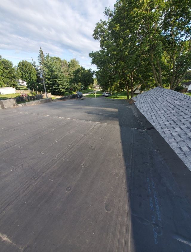 A roof with a lot of shingles on it and trees in the background
