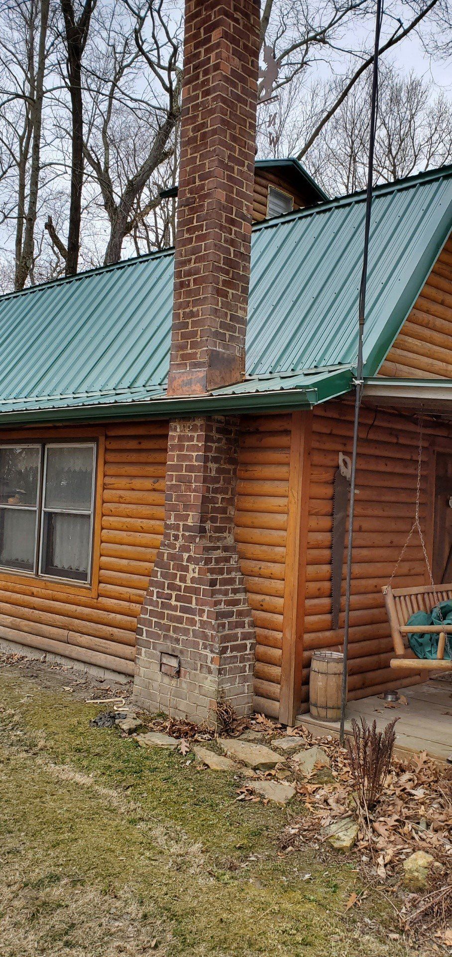 A log cabin with a green roof and a chimney.