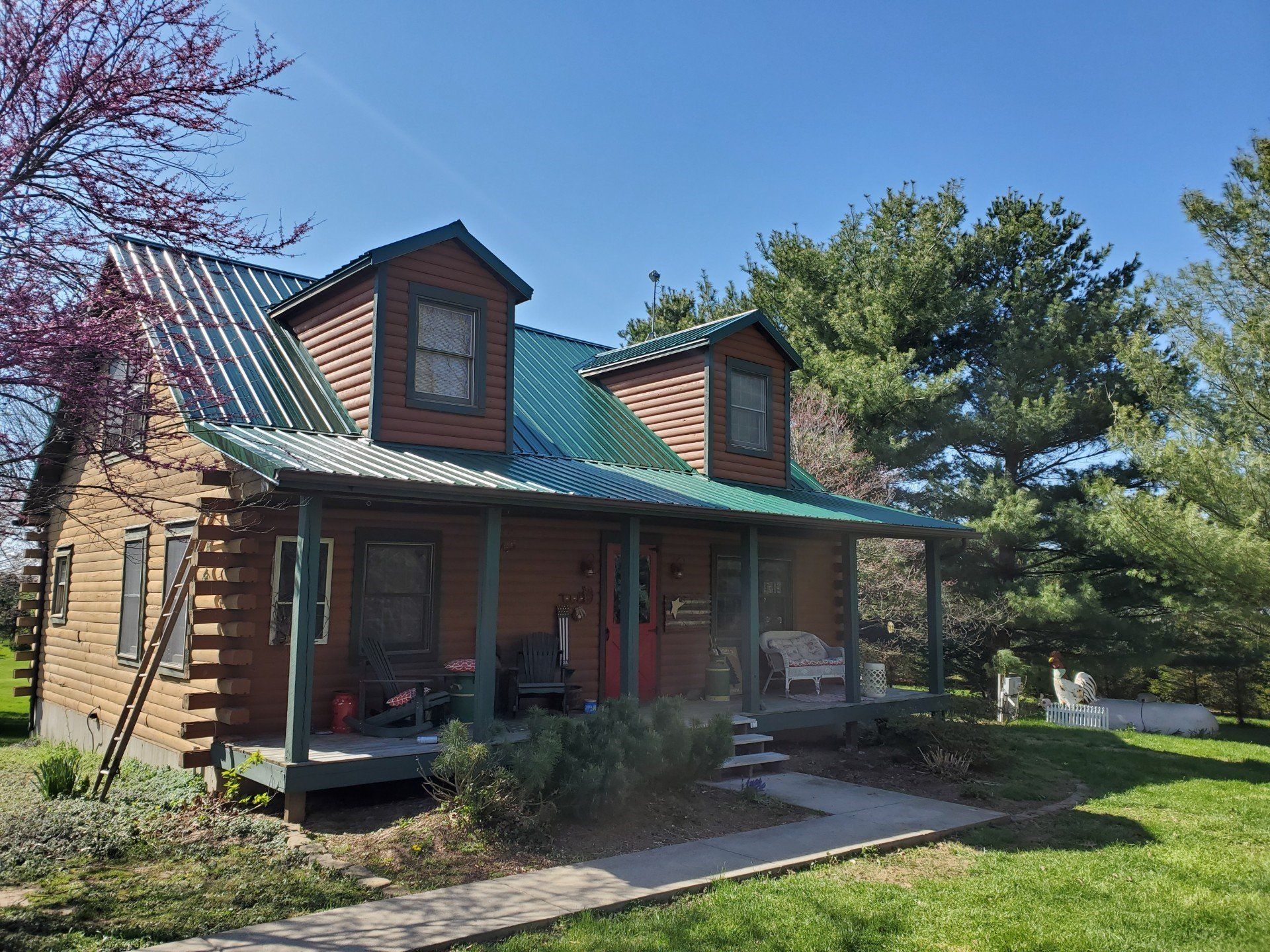 A log cabin with a green roof and a porch