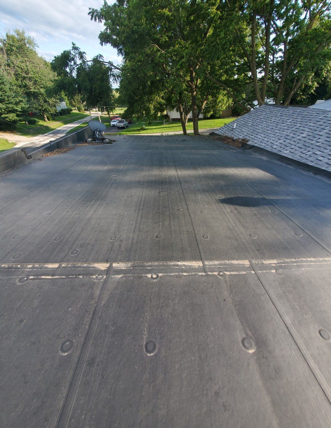 A black roof with a lot of trees in the background