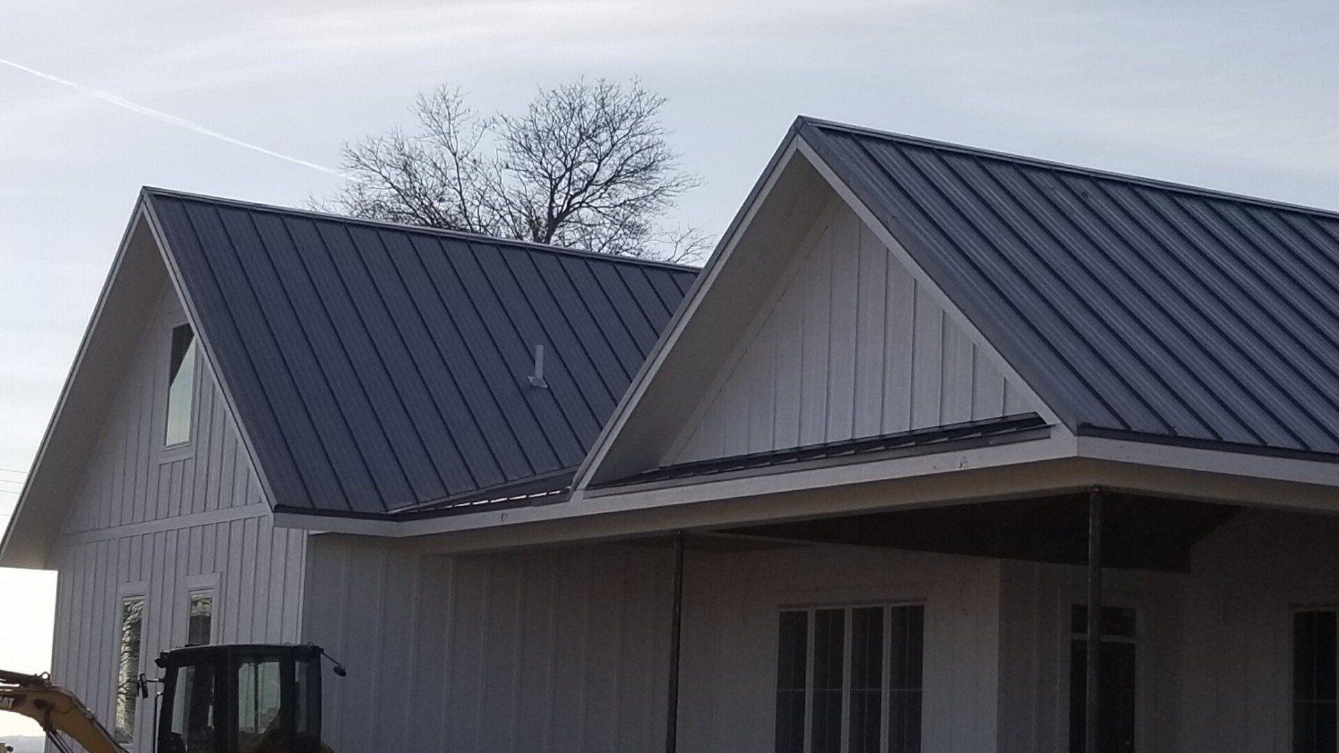A white house with a black roof is being built.