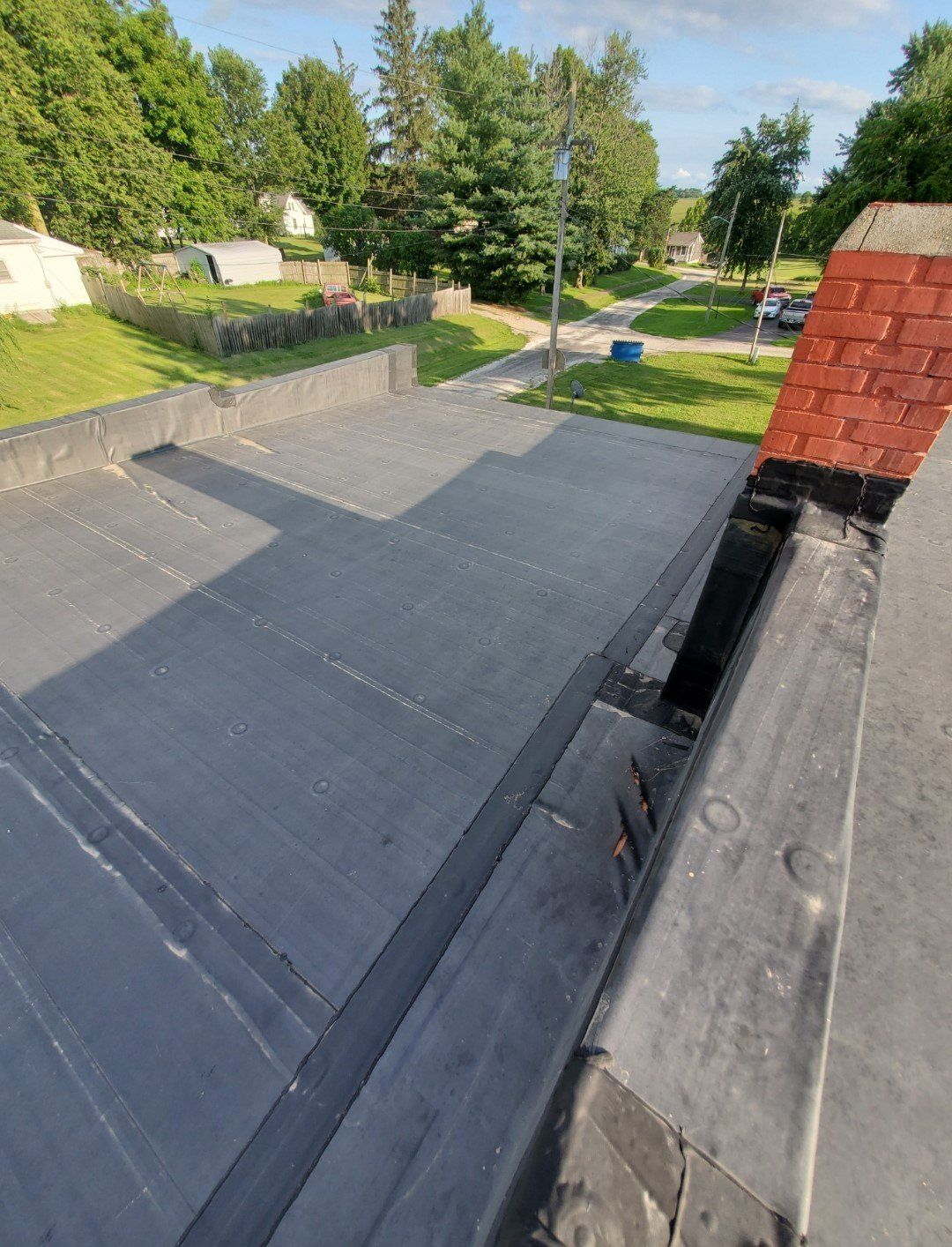 A roof with a chimney on it and trees in the background.