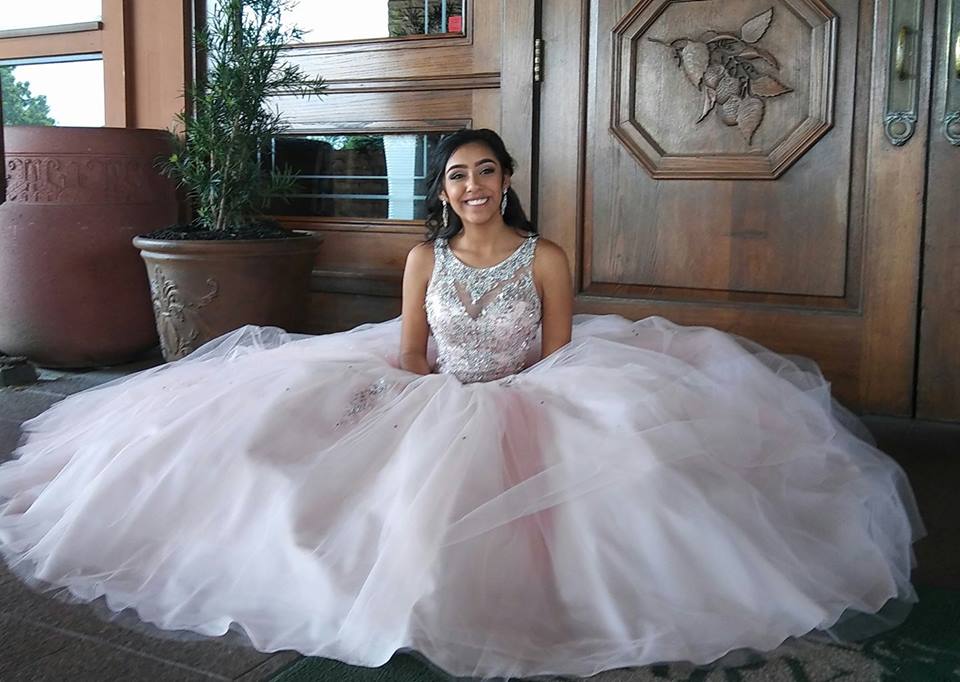A woman in a ball gown is sitting in front of a wooden door.