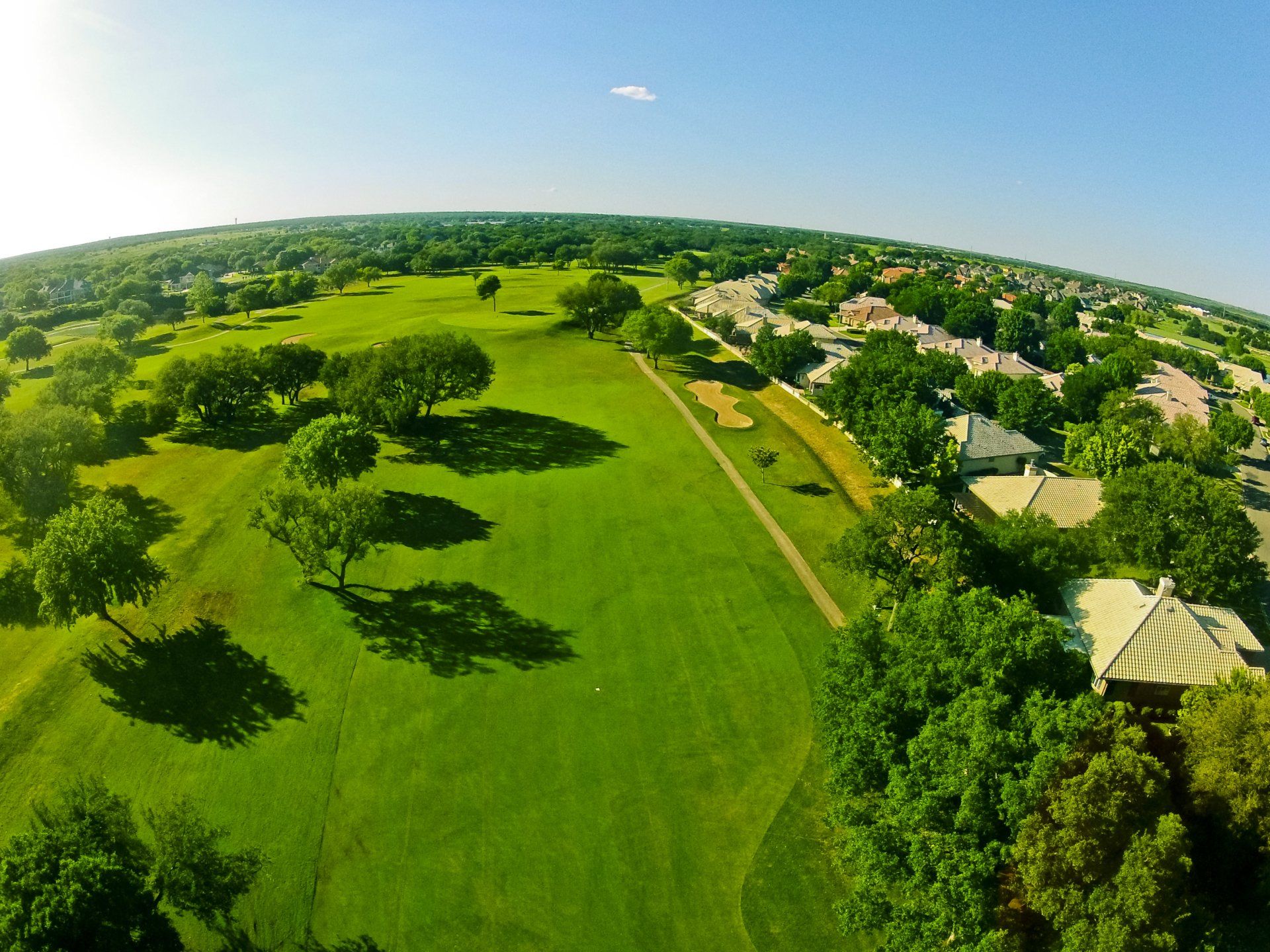 An aerial view of a golf course surrounded by trees and houses
