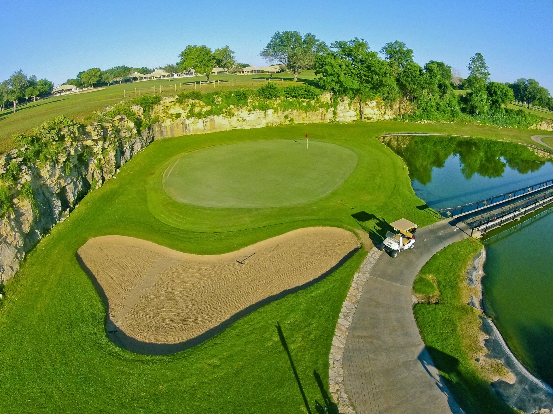 An aerial view of a golf course with a lake in the background