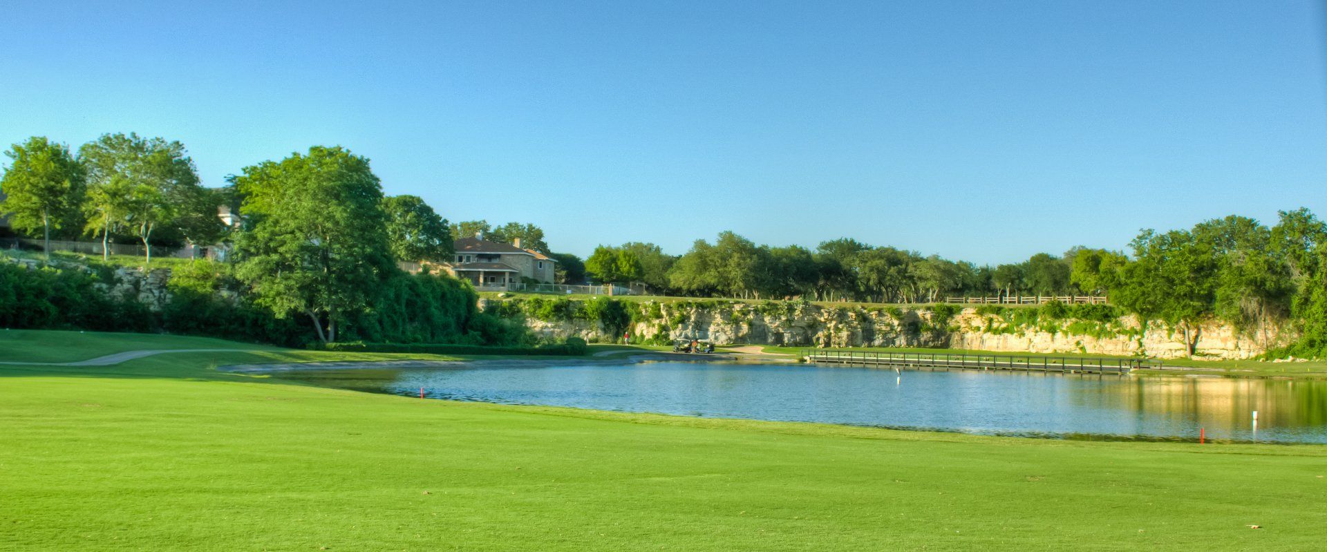 There is a pond in the middle of a golf course.