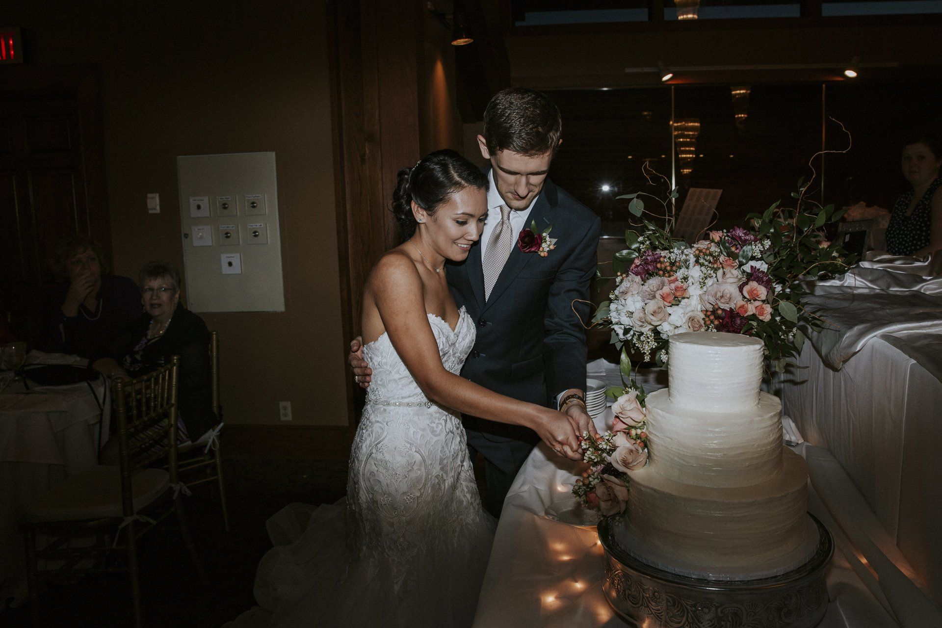 A bride and groom are cutting their wedding cake together.