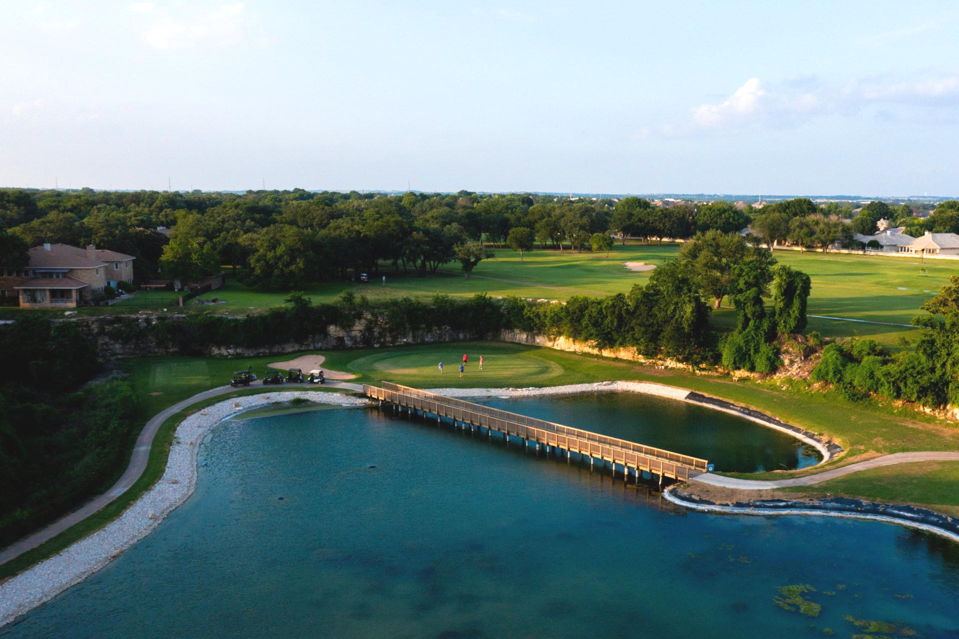 An aerial view of a golf course with a bridge over a lake.