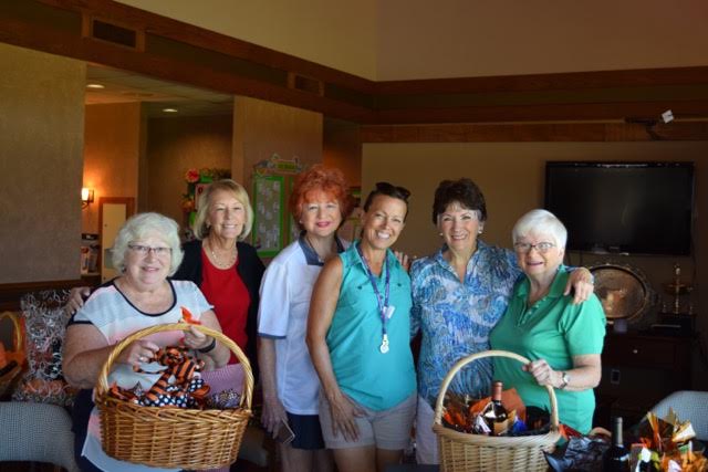 A group of women are posing for a picture while holding baskets.