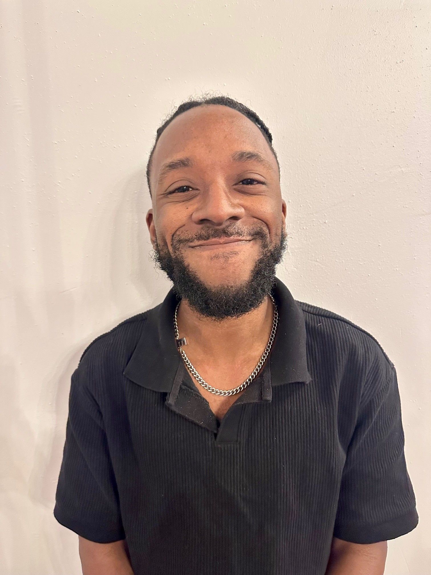 A man with a beard is wearing a black shirt and smiling for the camera.