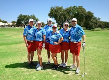 A group of people are posing for a picture on a golf course.