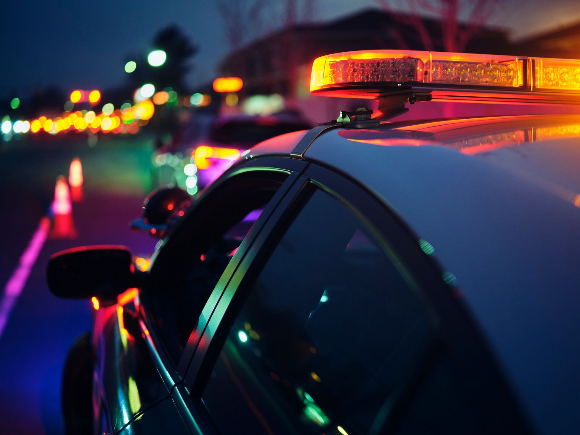 A police car with a light on top of it is parked on the side of the road at night.