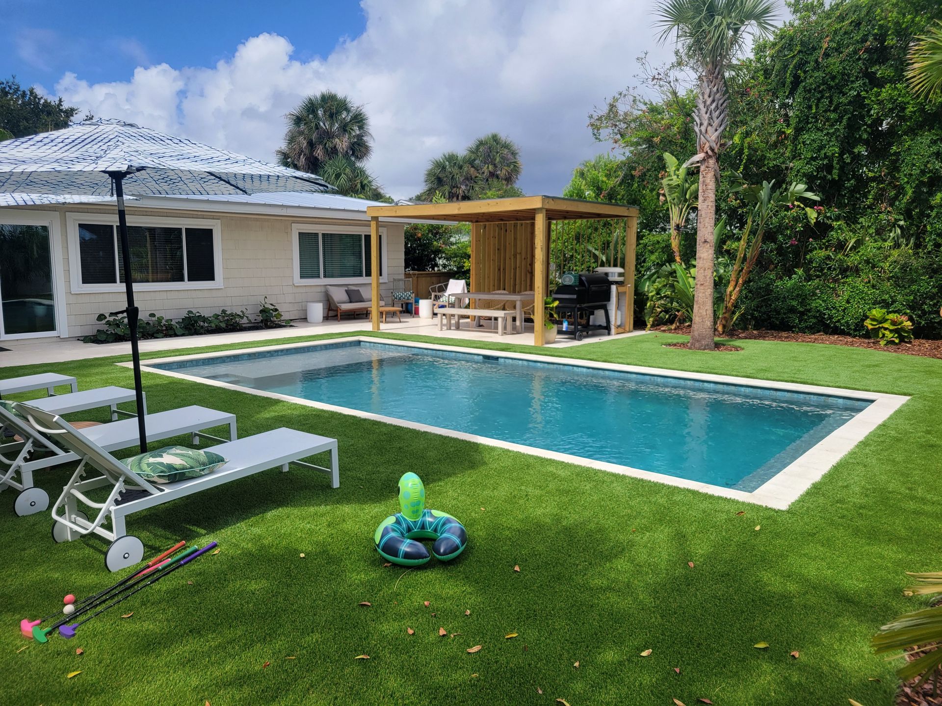 There is a large swimming pool in the backyard of a house.