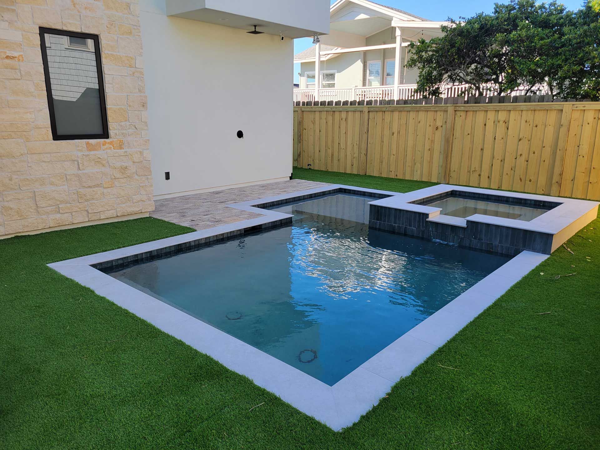 A small swimming pool in a backyard with a wooden fence surrounding it.