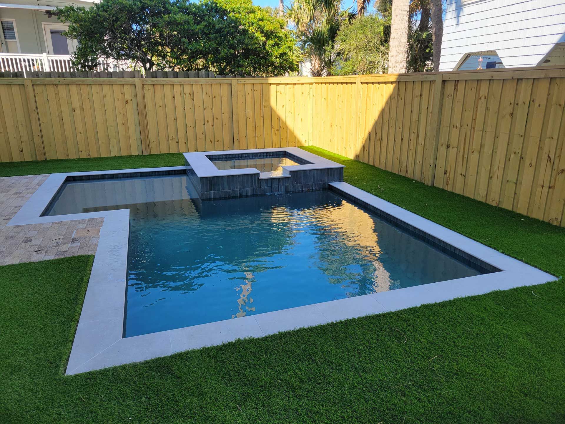 A small swimming pool in a backyard with a wooden fence surrounding it.