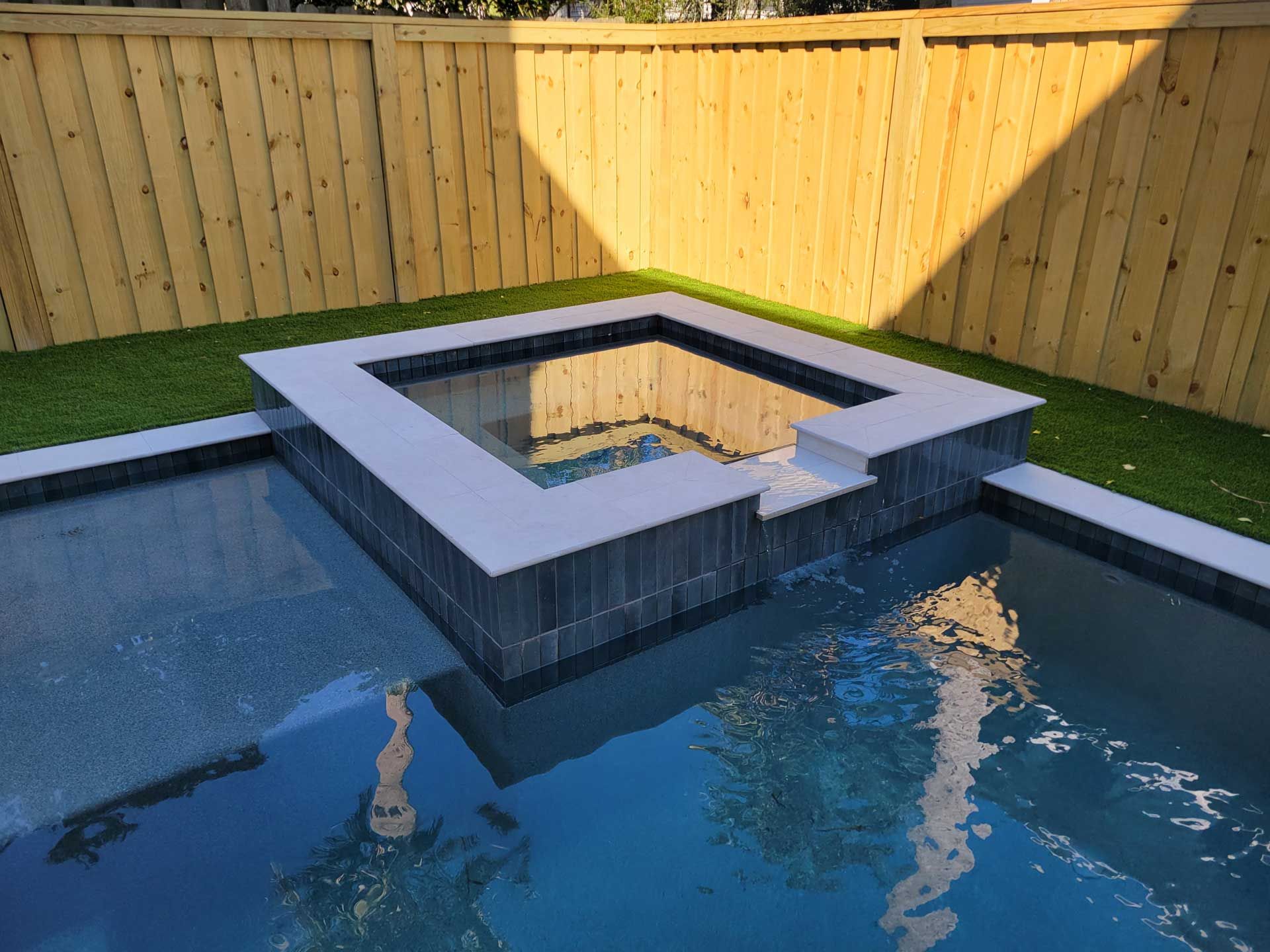 A swimming pool with a hot tub in the middle of it.