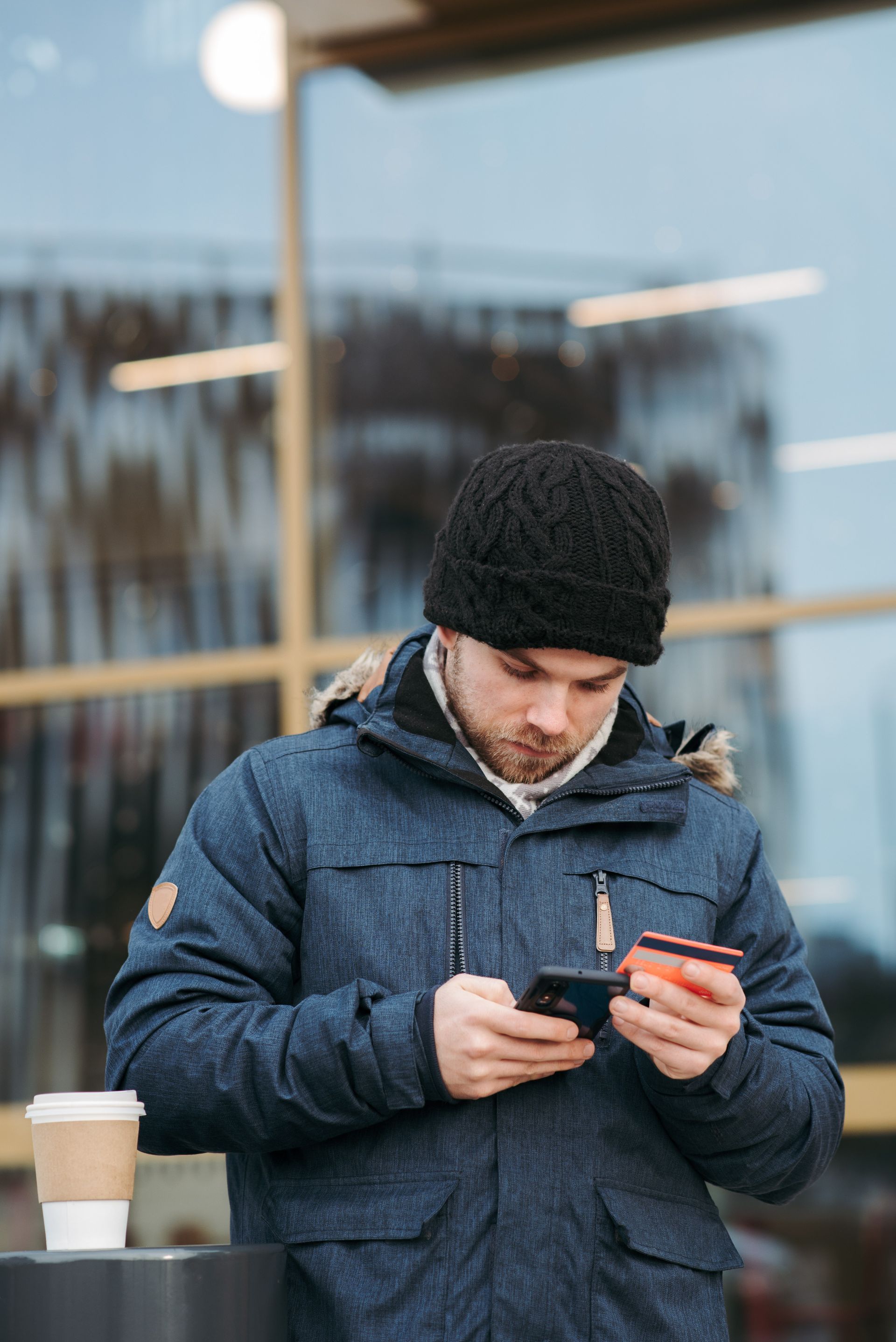 A man is holding a credit card and a cell phone.
