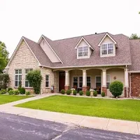 Suburban house with stone siding, dormer windows, and a front porch, bordered by a green lawn