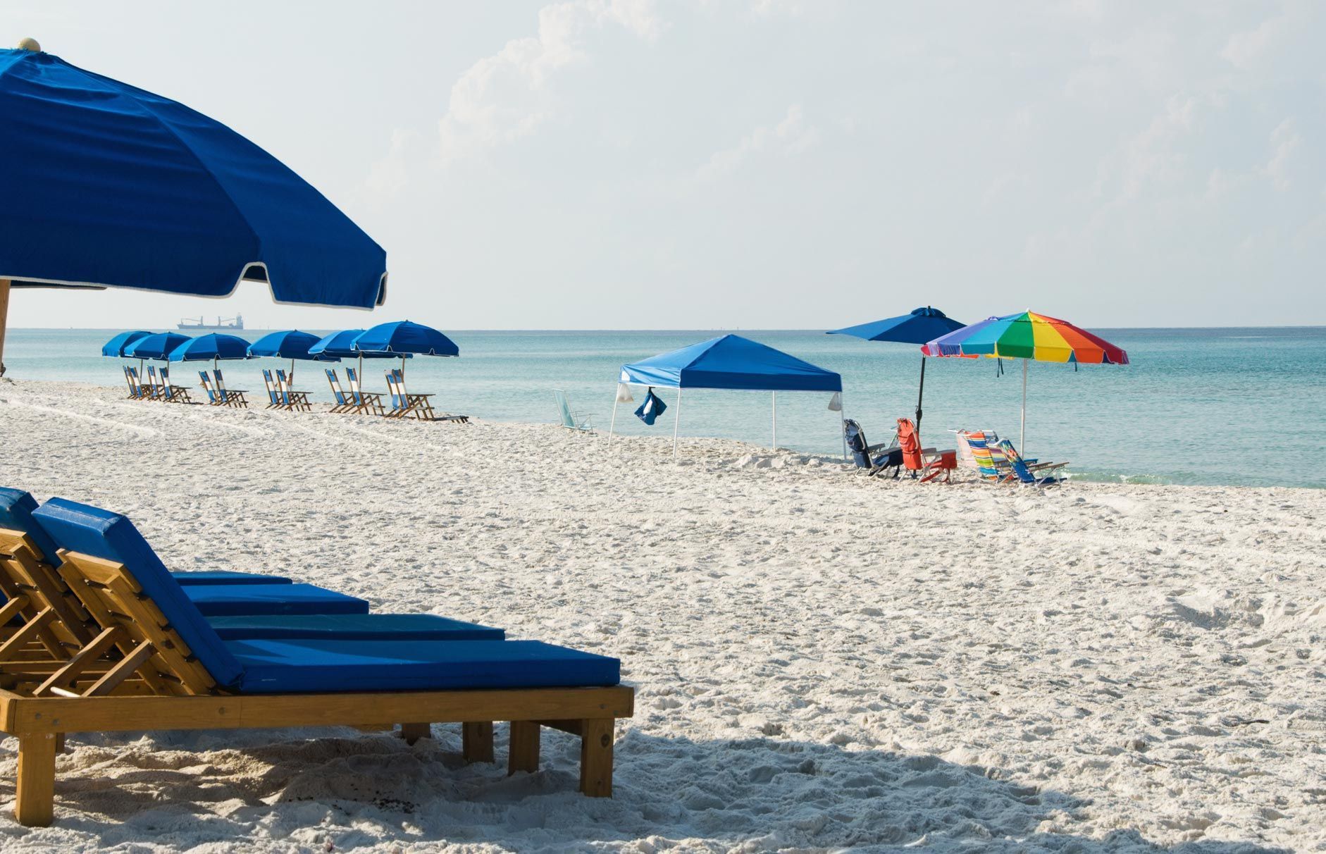 A beach with blue chairs and blue umbrellas