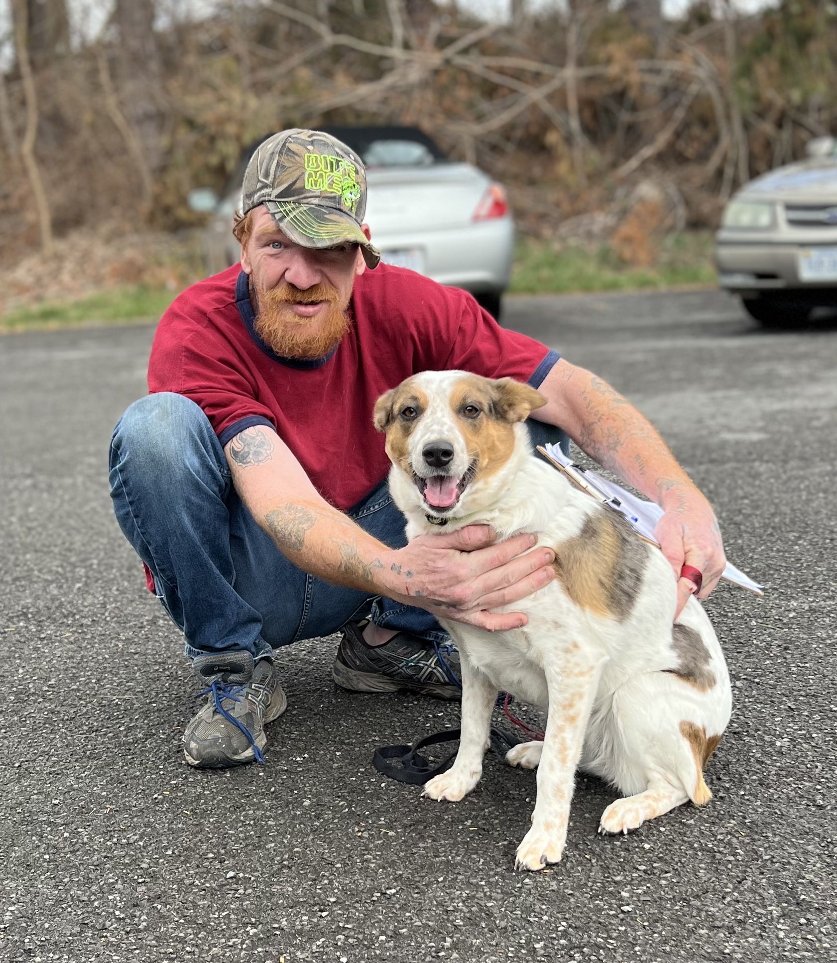A man kneeling down to hug his dog and looking very happy.
