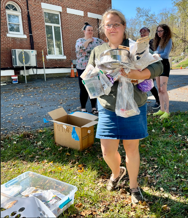 A young lady carrying pet supplies at a volunteer event.