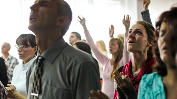 a group of people praying with their hands in the air