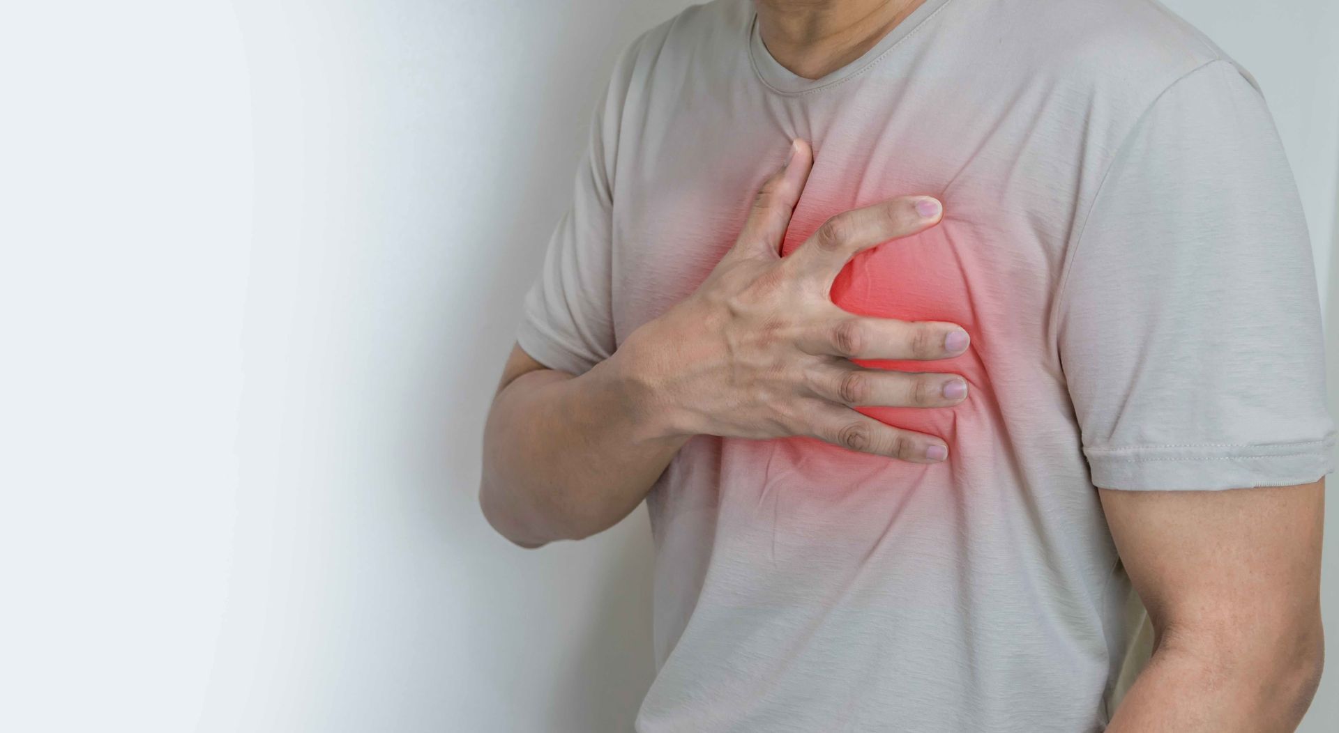 Person clutching chest with red highlight indicating chest pain or heart discomfort